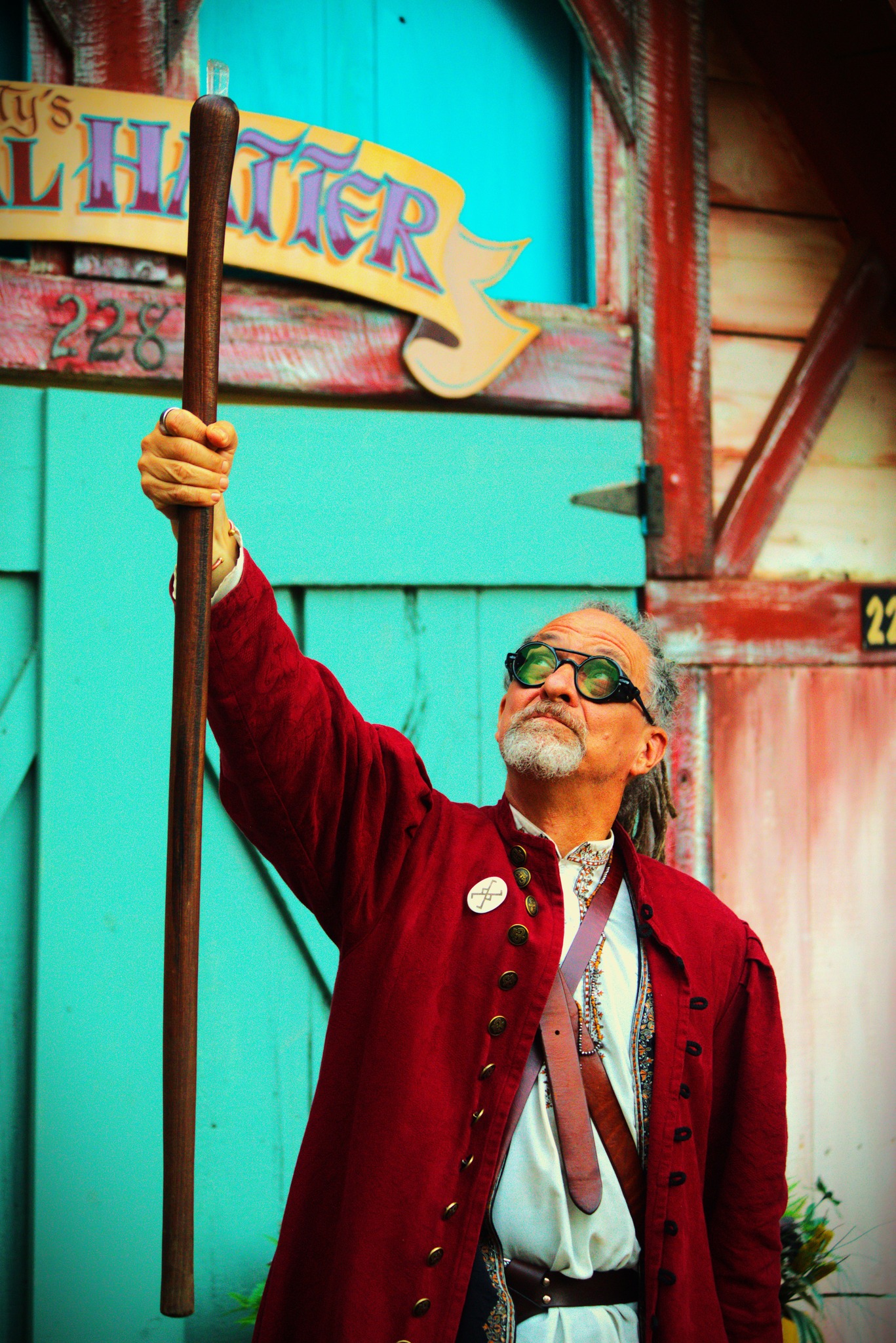 Mossbeard lifting his staff before the Mad Hatter sign